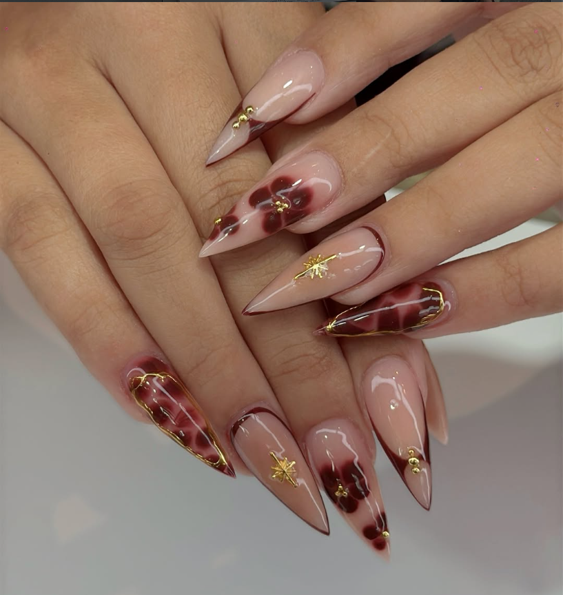 Red floral almond nail art with gold accents at Jovial Beauty